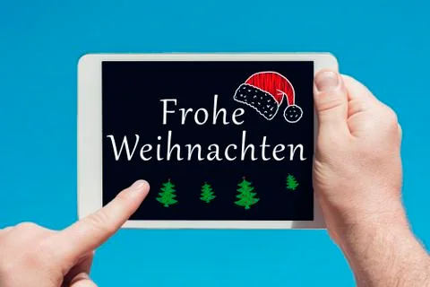Man holding a tablet device with text in German "Frohe Weihnachten" (Merry Ch Stock Photos