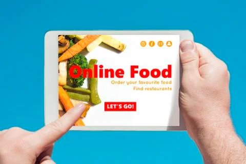 Man holding a tablet device visiting an online food website and touching the Stock Photos