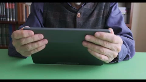 Man Holding Tablet for Digital Reading in a Cozy Library Setting. Dolly Stock Footage 309095493