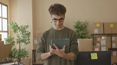 Man holding tablet, hands tapping screen amid stacked parcels in a delivery.. Stock Footage 337435317