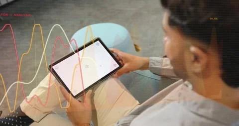 Man holding tablet on sofa tilting device and testing tech waves overlaying Stock Footage 334175968