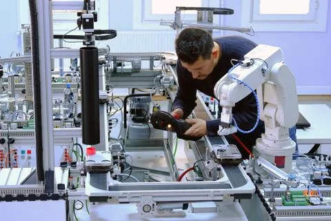 Man is holding teach panel to control a robot arm on smart factory Stock Photos