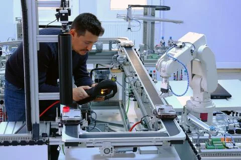 Man is holding teach panel to control a robot arm on smart factory Stock Photos