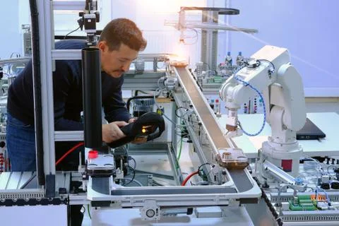Man is holding teach panel to control a robot arm on smart factory Stock Photos