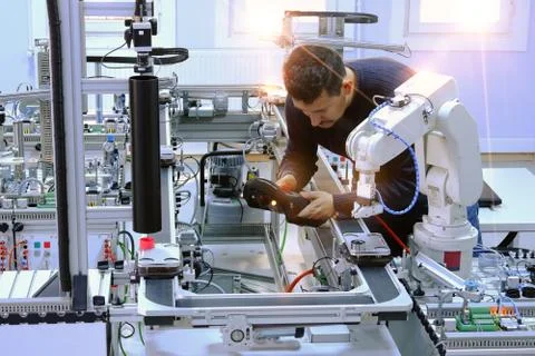 Man is holding teach panel to control a robot arm on smart factory Stock Photos