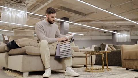 Man holding textile swatches, comparing different fabric options for new sofa Stock Footage 334654198