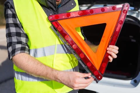 A man holding a triangular sign of an accident Stock Photos