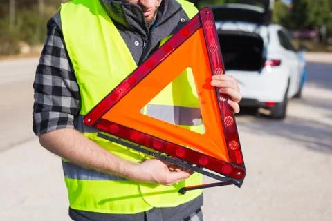 A man holding a triangular sign of an accident Stock Photos