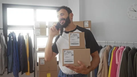 Man holding two cardboard boxes in a small ecommerce studio while talking o.. Stock Footage 347813465
