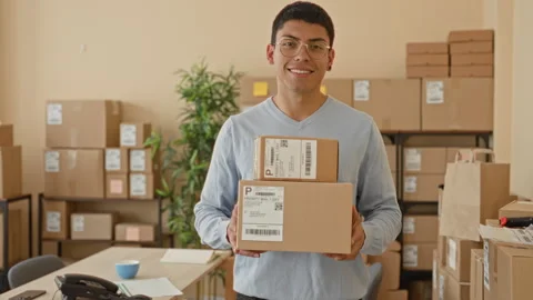 Man holding two shipping boxes and smiling while presenting parcels at ches.. Stock Footage 337431600