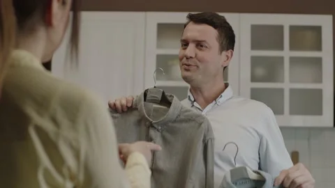 The man holding two shirts cannot decide which shirt to wear. Stock Footage 203536288