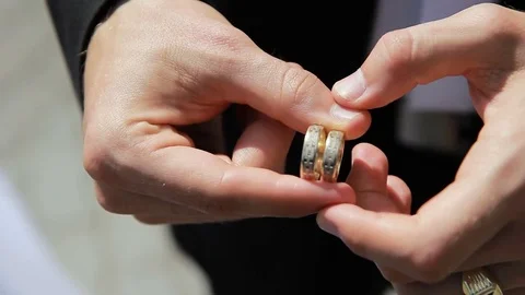 Man holding two wedding rings in his hands and turns them around Stock Footage 76382575