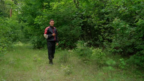 Man holding typing smartphone looking at camera in forest Stock Footage 158142260