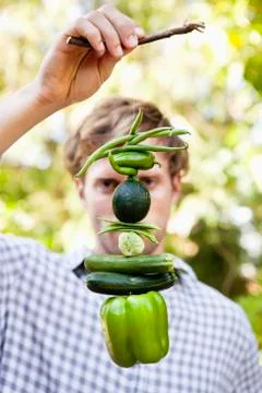 Man holding vegetables hanging on a twig Stock Photos