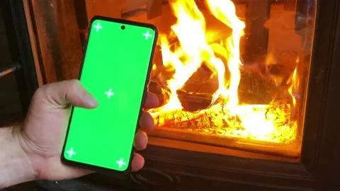 Man Holding a Vertical Green Screen Smartphone, Fire Background. Stock Footage 220710638