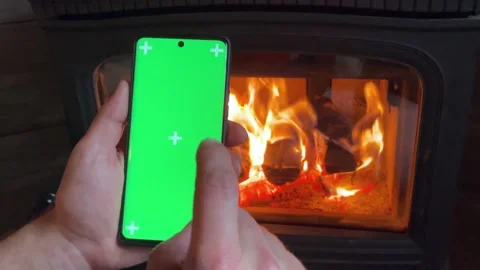 Man Holding a Vertical Green Screen Smartphone, Fire Background. Stock Footage 220710700