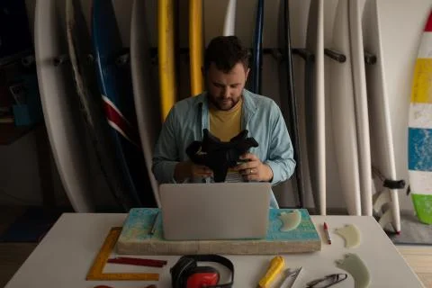 Man holding virtual reality headset while using laptop in a workshop Stock Photos