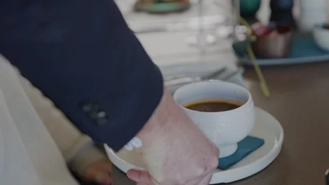 A man is holding a white coffee cup with a blue coaster Stock Footage 306576685