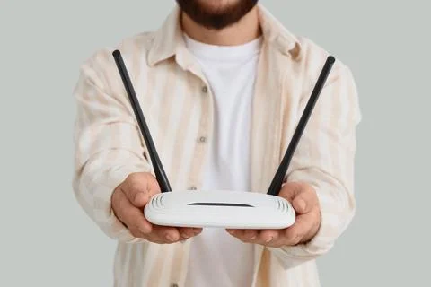 Man holding a white wireless router with two antennas, internet connection an Stock Photos