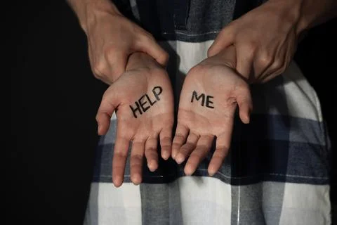 Man holding woman's hands with words HELP ME on dark background, closeup. Sto Stock Photos