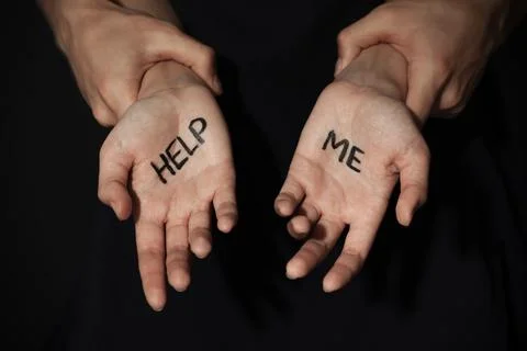 Man holding woman's hands with words HELP ME on dark background, closeup. Sto Stock Photos