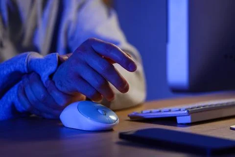 Man holding wrist while reaching for computer mouse Foto stock