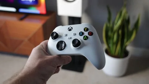 Man holding Xbox gaming controller in modern living room Stock Footage 265470392