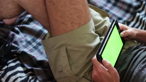 Man holds a blank tablet PC with a green screen on sofa Stock Footage