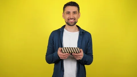 Man holds a box with a gift in his hands, smiles and looks at the camera Stock Footage 119861709