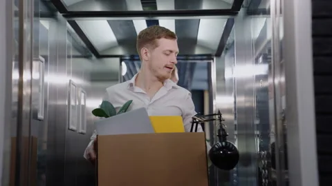 Man holds a box while choosing the right floor in the elevator in office Stock Footage 246051044