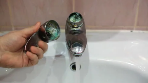 A man holds a broken tap valve in his hands. Defective water tap in the bathroom Stock Footage 124397016