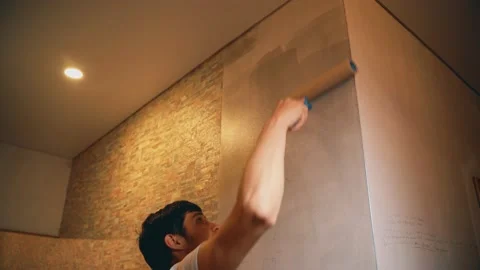 A man holds a brush in his hands and covers the putty wall with glue Vidéo 146041253