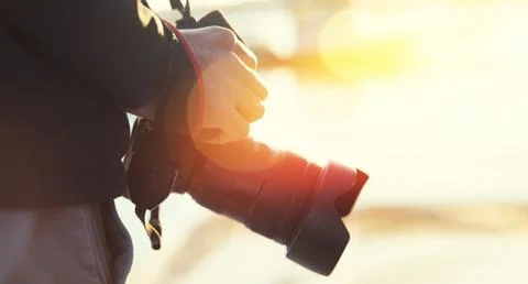 Man holds camera with hand in light sun. Concepts professional travel lifestyle 스톡 사진