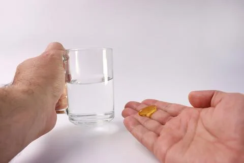 A man holds a capsule of a complex of polyunsaturated fatty acids and a gla.. Stock Photos