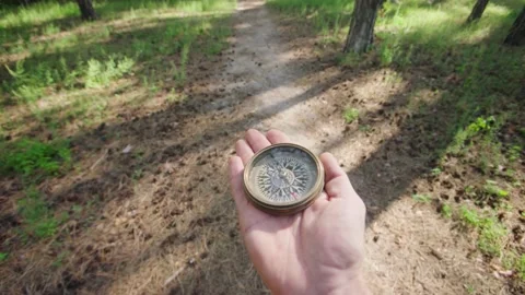 Man holds a compass in hand and looks for direction. Active lifestyle, hiking Stock Footage 210435375