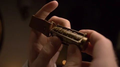 A man holds copper cryptex with numbers.He calculates cryptex code with his hand Stock Footage 105861232