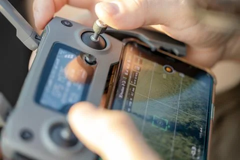 A man holds a drone remote control in his hands, controlling the drone from a Stock Photos