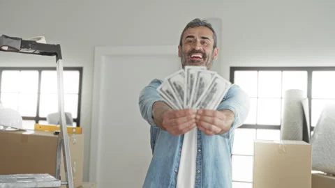 Man holds fan of dollars with both hands extended in building with moving b.. 스톡 동영상 339170555