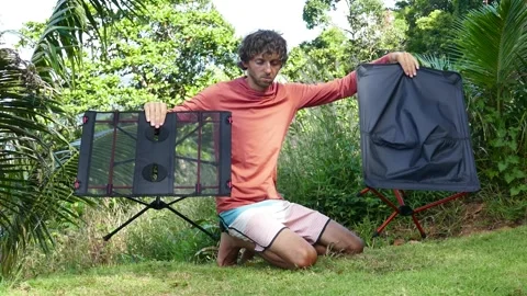 Man holds folding super light table and chair for camping and hiking Stock Footage 293755083