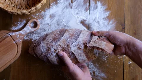 Man holds freshly baked bread, tearing off piece with anticipation. Breads crust Stock Footage 266803757