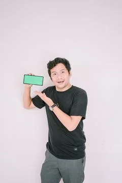 A man holds a greenscreen phone, pointing it towards the camera Foto stock