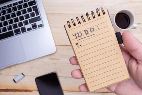 Man holds in hand a notepad. notebook, phone, cup of coffee near Stock Photos