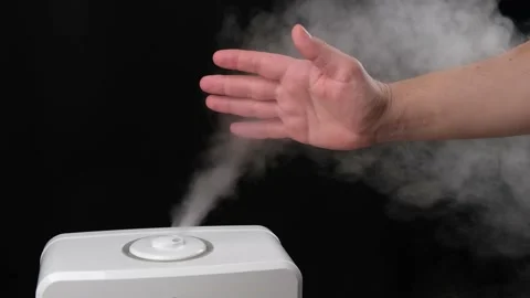 Man holds hand over steam from the air humidifier, free space. Slow motion. Stock Footage 147207452