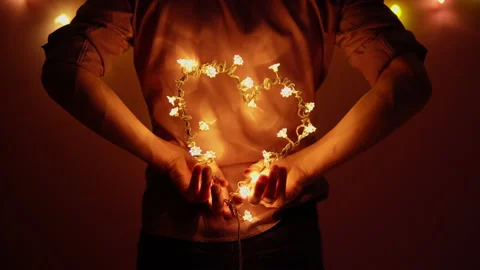 A man holds a heart made of light bulbs behind his back. Valentine's Day Stock Footage 147458422
