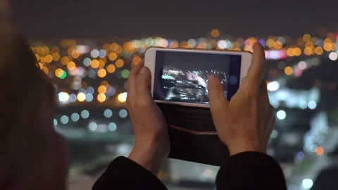 Man holds a horizontal smartphone on the background of a beautiful cityscape at Stock Footage 148648923