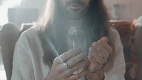 A man holds incense in his hands and blows on them Stock Footage 231114874