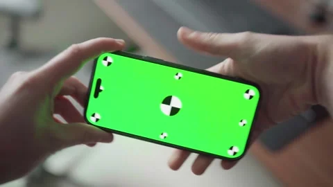 Man holds iPhone 16 Pro Max with green screen while rotating it from landscape Video stock 295131632