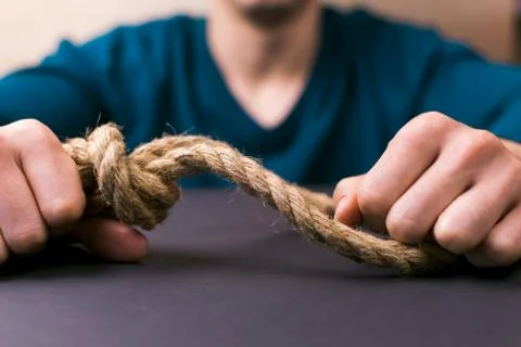 A man holds a loop of rope in his hands. A mental health day. Stock Photos