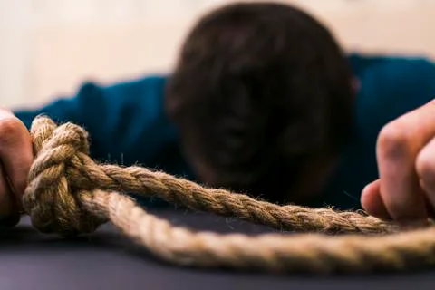 A man holds a loop of rope in his hands. A mental health day. Stock Photos