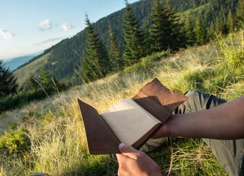 Man holds a notebook in his hands outdoors Stock Photos